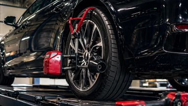 Black car with red wheel alignment equipment in workshop