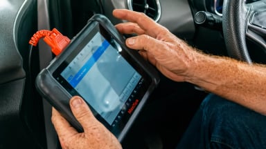 Person using a diagnostic tablet in a car